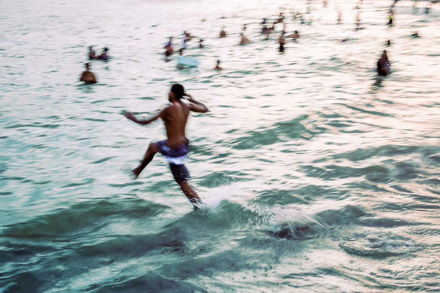 impressionism inspired mixed media photo of man running in to the surf at sunset