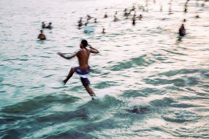 impressionism inspired mixed media photo of man running in to the surf at sunset